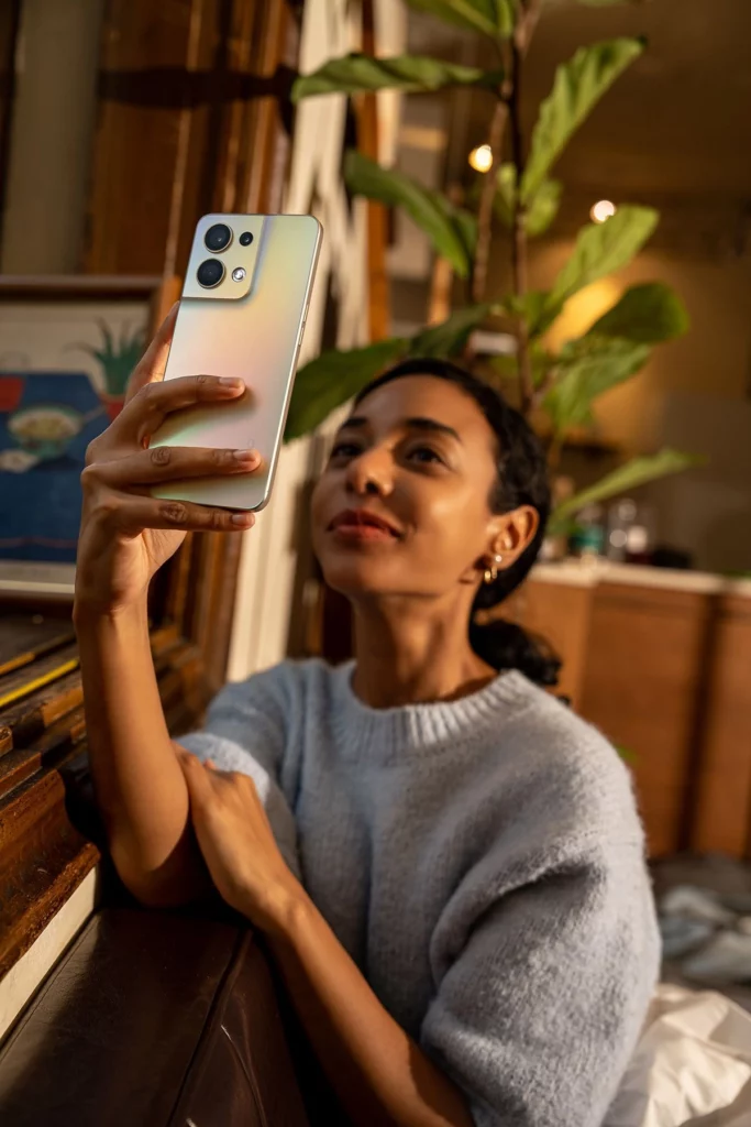 Femme métisse tenant un téléphone et consultant l’écran avec attention – Sahiya Method, accompagnement bien-être connecté.